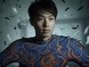 A young man, his shirt a whirlwind of blue and orange, stands amidst dancing black feathers in a luminous space, embodying ChaosProbe’s essence